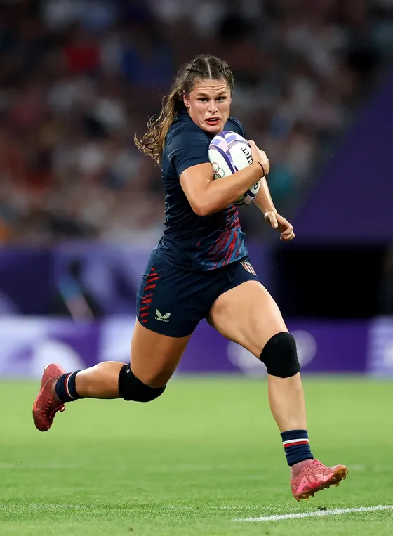 A rugby player sprinting upfield with the ball tucked under one arm